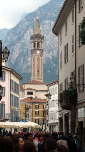 Street view of Lecco with tower and a mountain in the background.